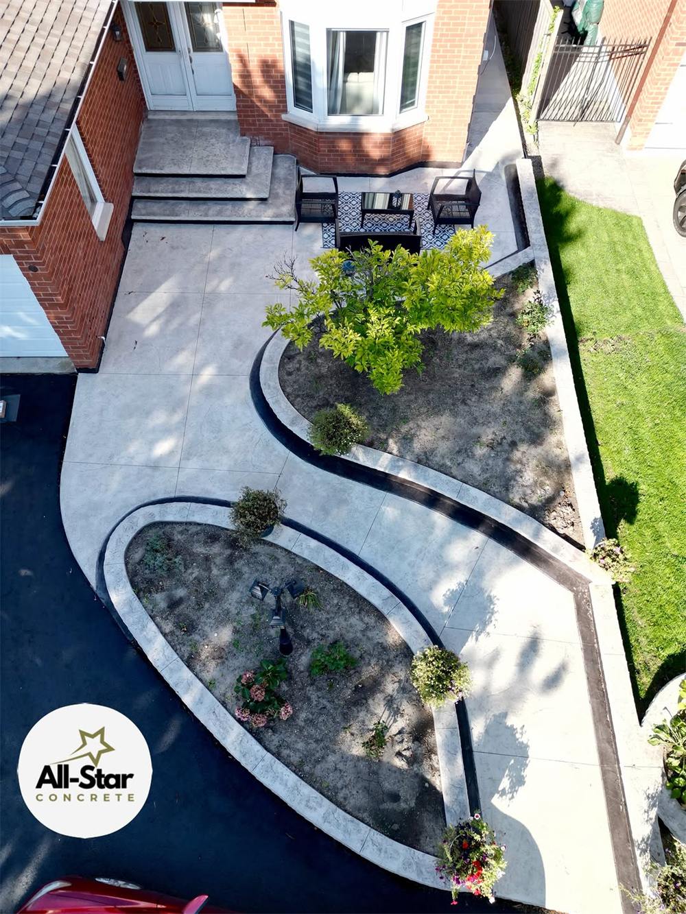Curved concrete walkways and garden beds beside a fresh driveway, from above